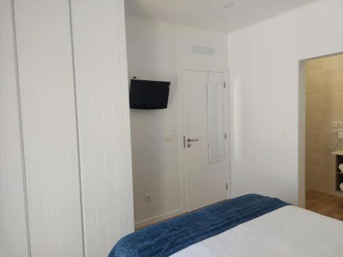 a bedroom with a bed and a tv on a wall at Lagoa azul guest house II in Vila Nova de Milfontes