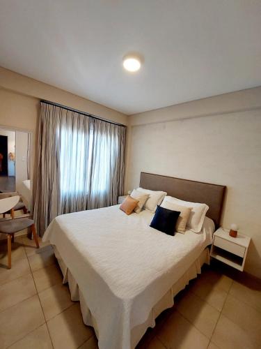 um quarto com uma cama grande com lençóis brancos e almofadas em DEPARTAMENTO CENTRICO em Santa Rosa