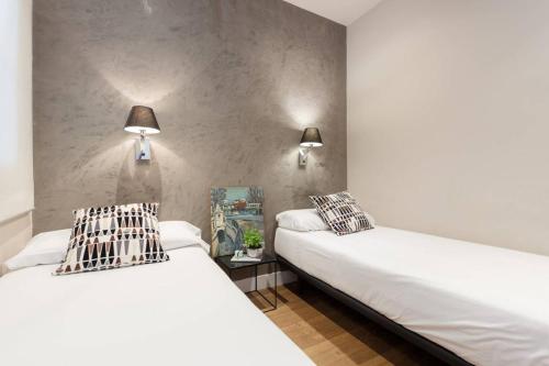 two beds in a bedroom with two lamps on the wall at Apartamento Casco-Antiguo Tarraco in Tarragona