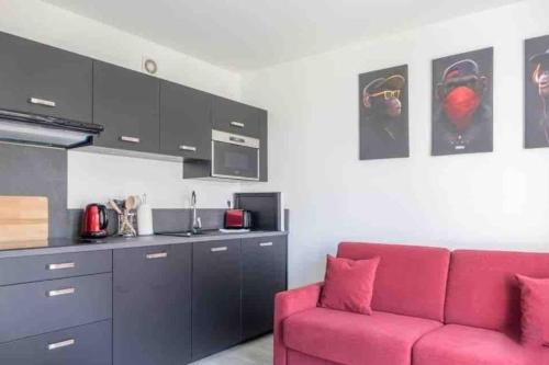 un salon avec un canapé rouge et une cuisine dans l'établissement Le Square des Sapins, à Orléans