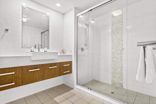 a white bathroom with a sink and a shower at Serenity Views in Airlie Beach