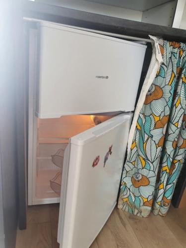 une porte de réfrigérateur ouverte avec un rideau à l'intérieur dans l'établissement Guest House entre ville et océan, à La Rochelle