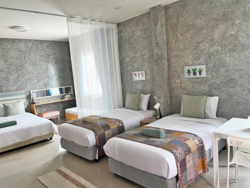a hotel room with two beds and a table at บ้านพักบุหงา199 แฟมิลี่ อ สรรพยา ชัยนาท in Ban Oi Noi (2)