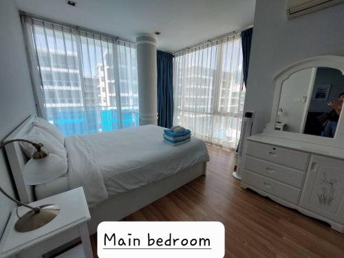 1 dormitorio con 1 cama grande y espejo en Light, airy, east facing 2 bed/2 bath pool views en Hua Hin