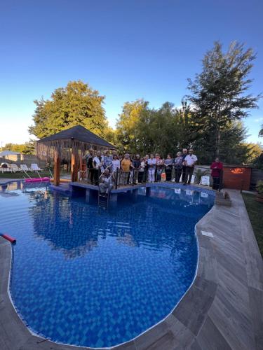 a group of people standing around a large swimming pool at Hotel Boutique Family Suites in Panguipulli