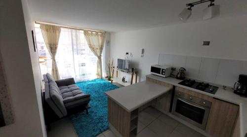 a kitchen and living room with a couch and a table at departamento cercano a mall zofri in Iquique