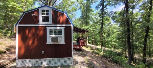 a small red house in the middle of a forest at The Americana - Parker Creek Bend Cabins in Murfreesboro