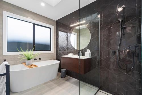 a bathroom with a tub and a sink and a mirror at CatchN'Relax Taupo in Taupo