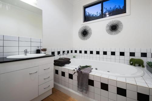 a white bathroom with a tub and a sink at Absolute in Daylesford