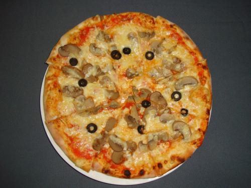 a pizza with mushrooms and black olives on a plate at Royal Astoria Hotel in Kathmandu