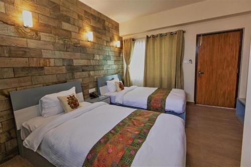 a hotel room with two beds and a stone wall at Pata Inn in Kathmandu