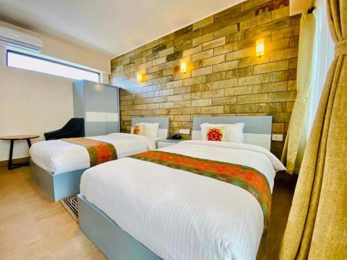 ein Hotelzimmer mit 2 Betten und einer Ziegelwand in der Unterkunft Pata Inn in Kathmandu