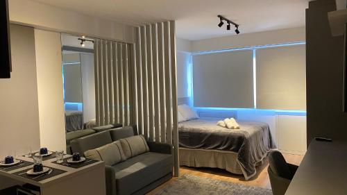 um quarto com uma cama, um sofá e um espelho em Studio LifeSpace Batel Curitiba em Curitiba