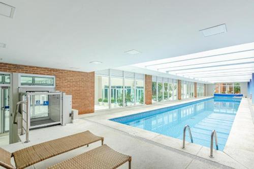 a large swimming pool with benches in a building at Studio LifeSpace Batel Curitiba in Curitiba