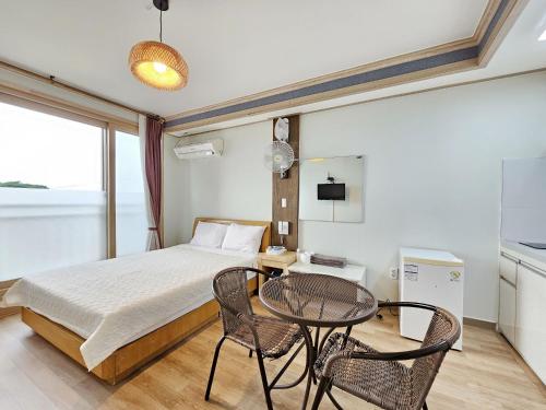 Red Castle Pension في جيجو: غرفة نوم بسرير وطاولة وكراسي
