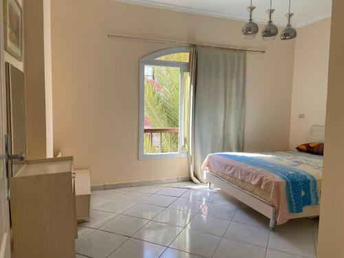een slaapkamer met een bed en een groot raam bij ديزرت بيرل in Hurghada