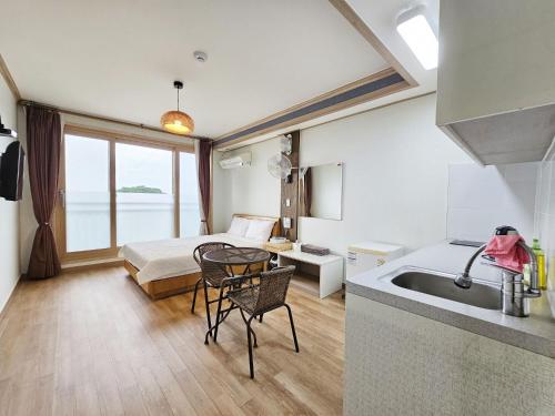 a bathroom with a bed and a sink in a room at Red Castle Pension in Jeju