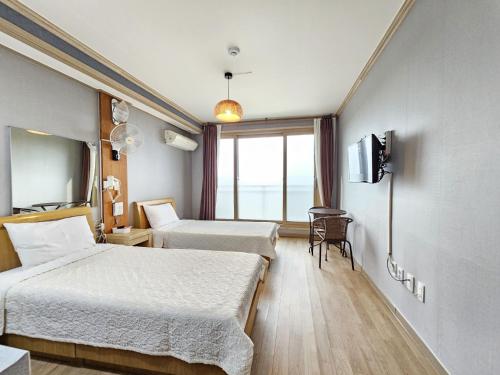 a hotel room with two beds and a window at Red Castle Pension in Jeju