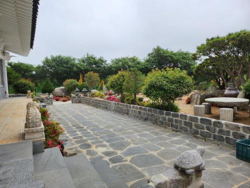a stone path in a garden with a stone wall at Seoak Stay in Gyeongju