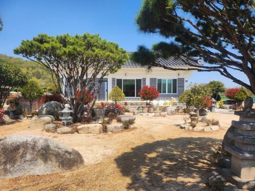 a garden in front of a house with trees and rocks at Seoak Stay in Gyeongju