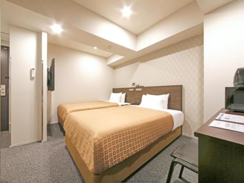 a hotel room with two beds and a desk at HOTEL LiVEMAX Chiba Chuo-Ekimae in Chiba
