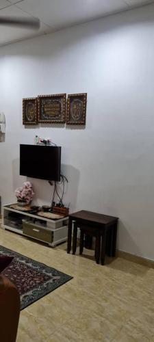 een woonkamer met een tv en een tafel bij NZ FAMILY HOMESTAY in Kota Bharu