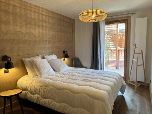 une chambre avec un grand lit et un lustre dans l'établissement Les Gets - Superbe appartement neuf au centre, proche des pistes et commodités - FR-1-623-344, aux Gets