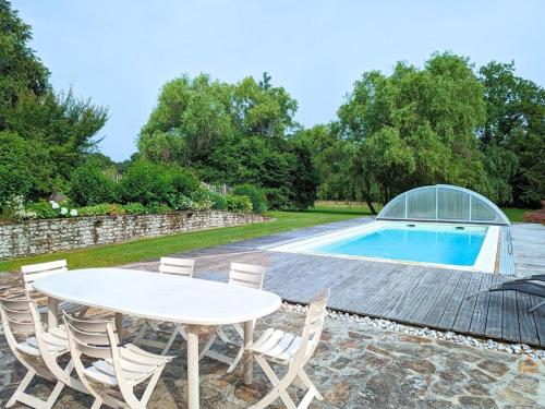 un patio avec une table et des chaises à côté d'une piscine dans l'établissement Gîte familial avec piscine couverte, jardin privé, proche d'Aubeterre-sur-Dronne - FR-1-653-239, à Bellon