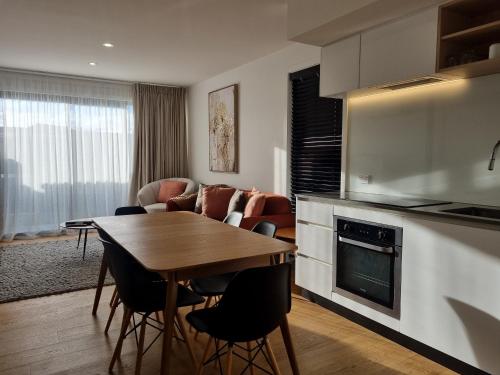 a kitchen and living room with a table and a couch at Alpine Junction Townhouse Apartments, Lodge & Hotel in Wanaka
