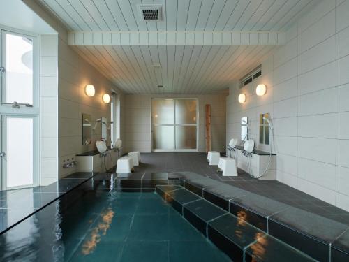 a bathroom with a pool of water with sinks and mirrors at Chateraise Lodge Atami in Atami