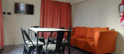 a living room with an orange couch and a table and chairs at Departamento DON ALBERTO in El Calafate
