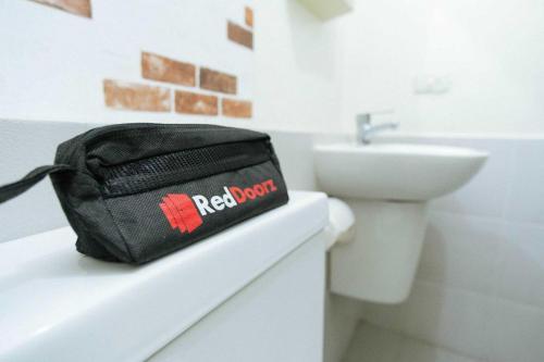 una borsa nera seduta su un bancone in bagno di RedDoorz @ Kings Hotel near CSB Mall a Cirebon