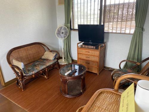 a living room with a couch and a tv at Sun Sea GuestHouse in Yomitan