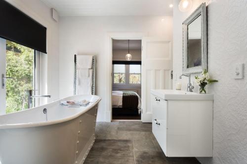 a white bathroom with a tub and a sink at Annecy House in Daylesford