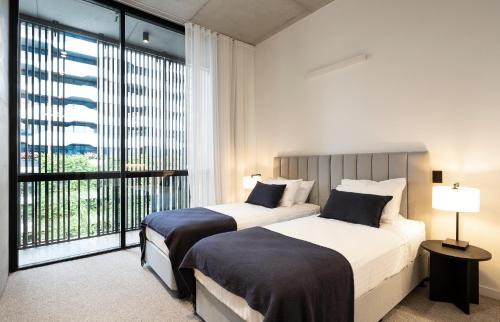 two beds in a bedroom with a large window at Alfred & Turner Apartments, Luxury 2 Bedroom Condos in heart of the Valley in Brisbane