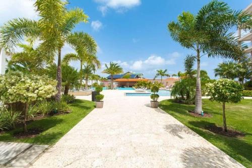 a pathway through a resort with palm trees and a pool at LUXURIOUS APARTMENT IN LEVENT FRONT EAGLE BEACH in Palm-Eagle Beach