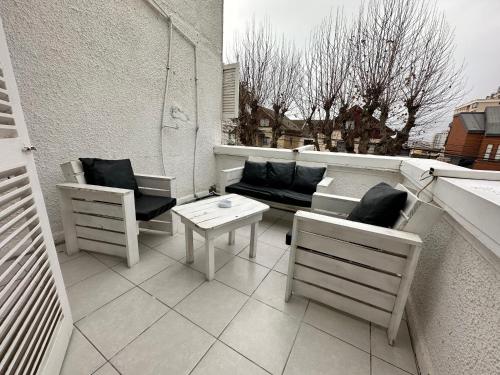 a balcony with a couch and chairs and a table at New York Suites in Viña del Mar