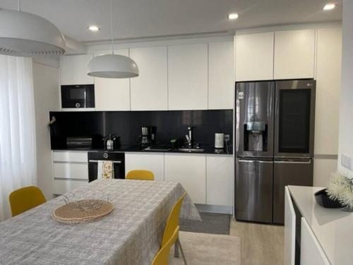 a kitchen with a table and a stainless steel refrigerator at Modern 1 Bedroom City Center Aveiro Apartment in Aveiro