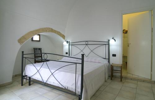 1 dormitorio con cama y puerta abovedada en B&b Altrov'è, en Parabita