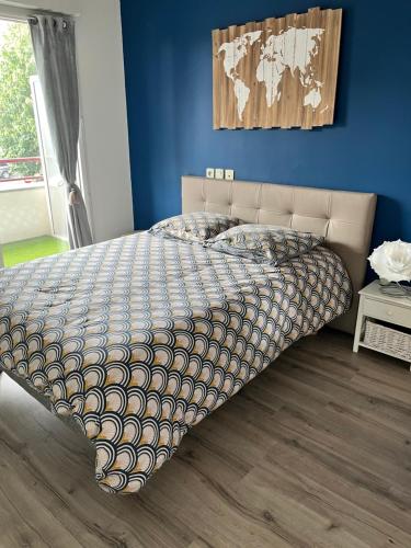 Bett in einem Schlafzimmer mit blauer Wand in der Unterkunft Charmant appartement la Roche sur Yon in La Roche-sur-Yon