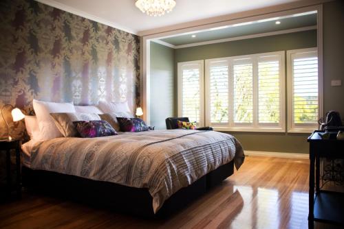 a bedroom with a large bed and a chandelier at Aroona in Daylesford