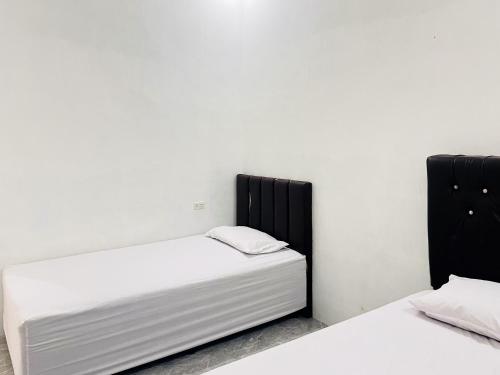 two beds in a room with white walls at RedDoorz Syariah @ Binjai Timur in Binjai