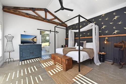 1 dormitorio con cama con dosel y baño en Cariad Private Country Hideaway at Mount View - stunning 360d viewss, en Mount View