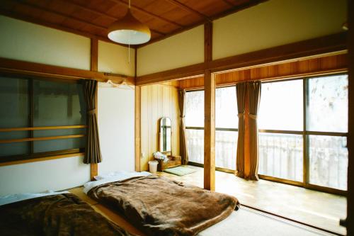 a bedroom with a bed and a large window at Hostel&Bar CAMOSIBA in Yokote