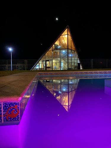 un gran edificio de cristal con luces púrpuras delante de él en Cabaña Cumbre Algarrobo, en Algarrobo