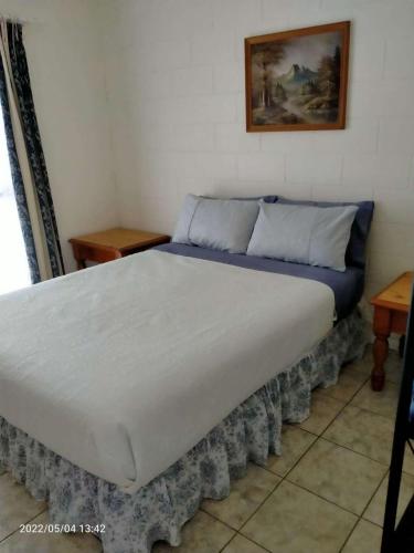 ein großes Bett in einem Zimmer mit 2 Tischen in der Unterkunft Tamarind Gardens Camping, Caravans, Accommodation in Almaden