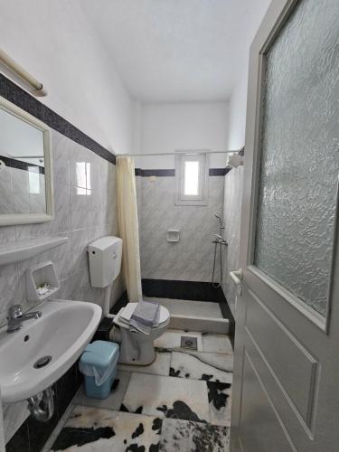 a bathroom with a sink and a toilet and a door at Korali Garden in Naxos Chora
