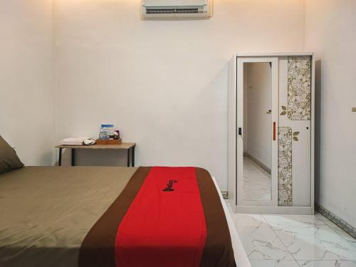 um quarto com uma cama com um cobertor vermelho em RedDoorz Syariah at Naffa Homestay em Sarolangun