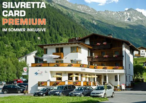a large building with cars parked in a parking lot at Berghotel Rasis in Galtür
