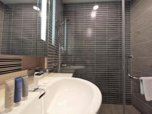 a bathroom with a white sink and a shower at Trinidad Suites Johor, Trademark Collection by Wyndham in Nusajaya